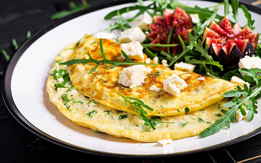 Omelette with feta cheese, parsley and salad with figs, arugula